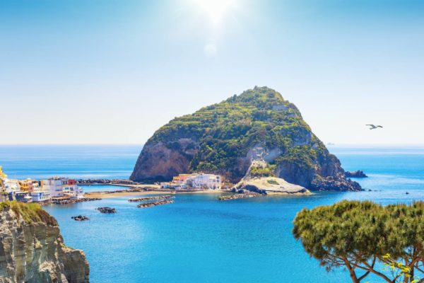 Panoramic view of giant rock with green trees on top near small village Sant'Angelo on Ischia island, Italy